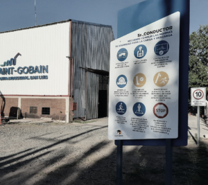 Tablero de cartelería de seguridad para conductores junto a una planta industrial